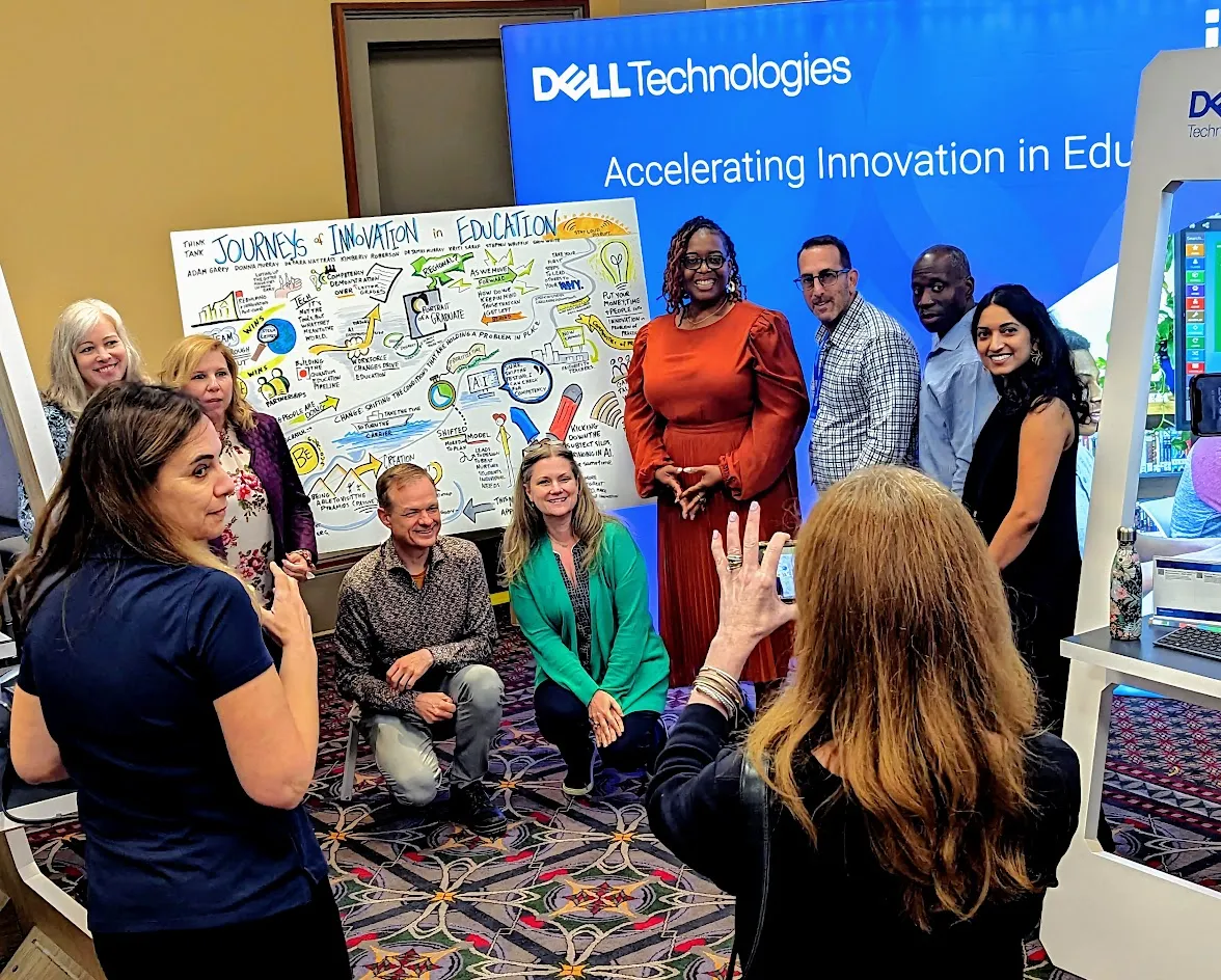Panel Discussion Speakers posing with a graphic recording created during their vendor-led conference session at a technology education event. 