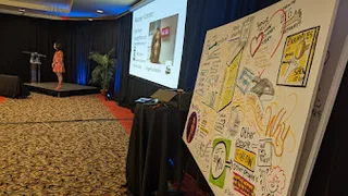 Graphic recording board set up in front of a small conference stage