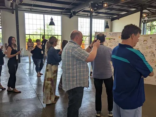 A large number of real estate agents taking photos of panels that represented keynote and breakout sessions at a conference in Louisville, Kentucky.