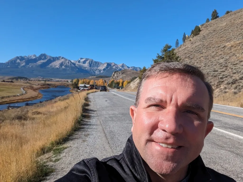 Matt standing next to a mountain river on a road east of Stanley, ID.  Sawtooth Mountains seen in the far distance.