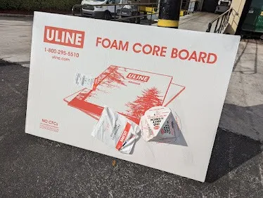 A box of ULINE foam core boards in an outside setting.